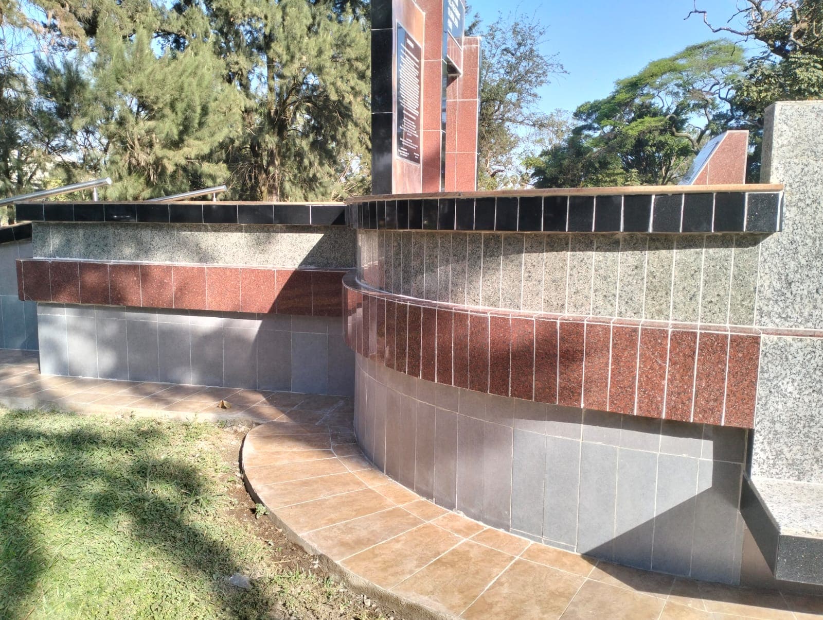 Curved feature wall re-clad in banded grey and red granite tile, with a new tiled walkway