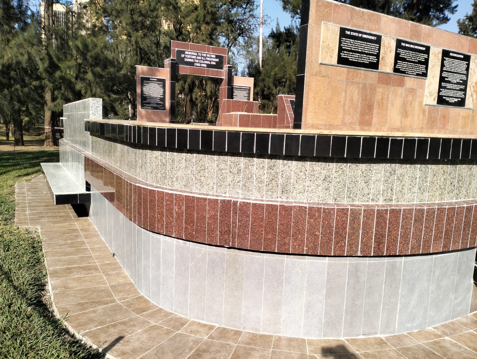 The long curved memorial wall with its history plaques after re-cladding in banded granite tile