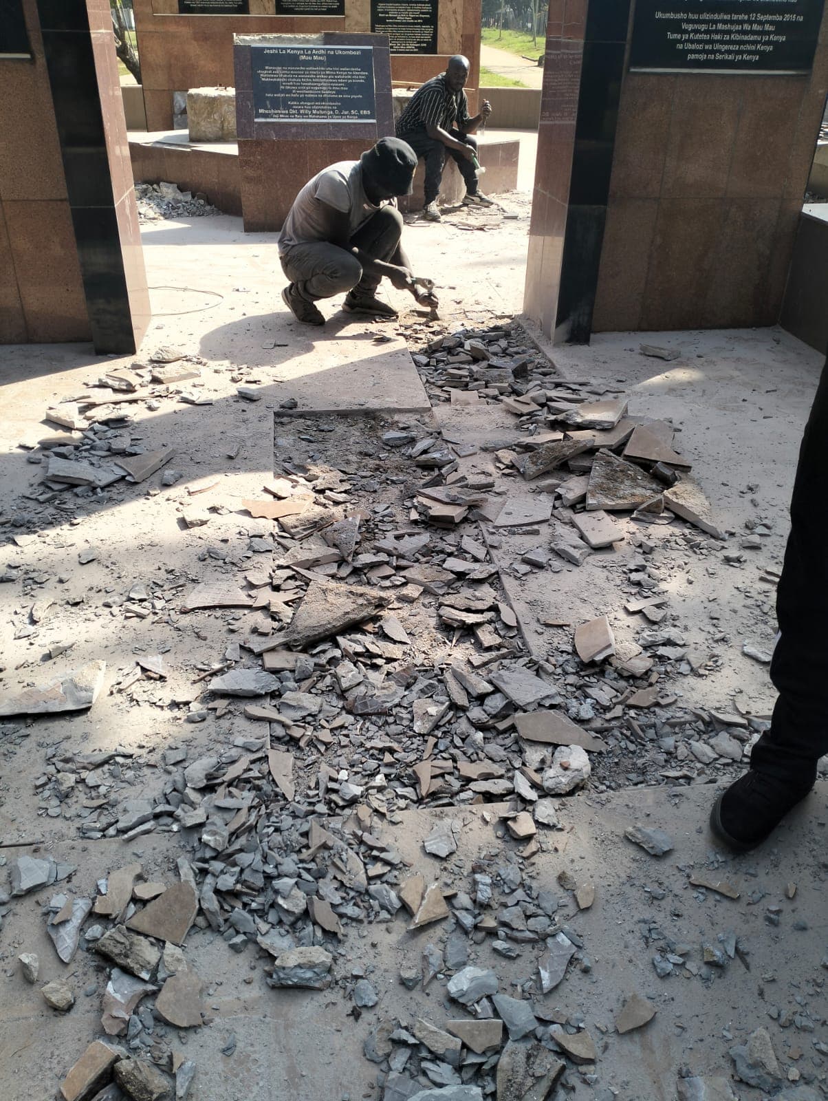 Workers breaking out cracked slate paving across the plaza before new paving is laid