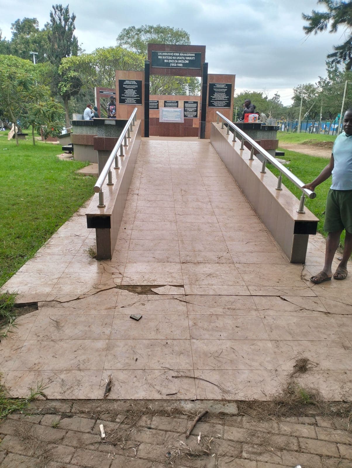 The tiled access ramp and stainless-steel handrails leading up to the memorial arch